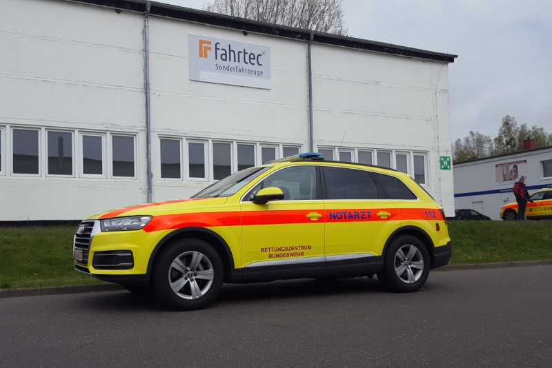 Abbildung zeigt ein gelbes Notarzteinsatzfahrzeug vor der Halle der Marke Audi Q7